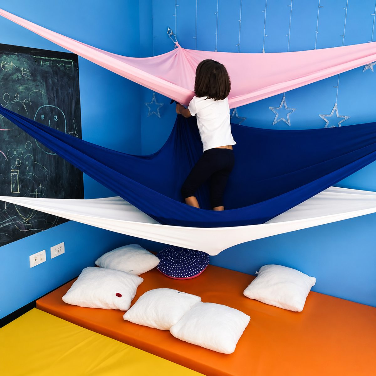 Teli sospesi colorati e materassi morbidi nella stanza del movimento del Centro Evoluzione Bambino